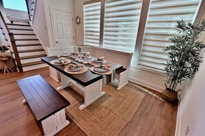 A dining area with a table set for four, a bench, and a staircase. - Rehoboth Beach Vacation Rental Luxury House at Arbor Lyn 6BR Home Sleeps 14 * New Listing * (Rehoboth Beach)