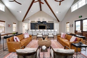 A spacious living area with sofas, a coffee table, and a dining area with chairs and a kitchen in the background.