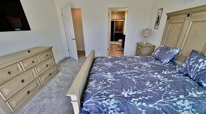 A bedroom with a bed, dresser, nightstand, and an open door leading to a bathroom. - Rehoboth Beach Vacation Rental Luxury House at Arbor Lyn 6BR Home Sleeps 14 * New Listing * (Rehoboth Beach)