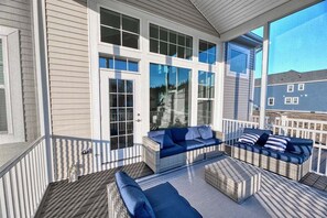 En overdækket terrasse med fletmøbler og en glasdør.