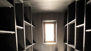 A narrow walk-in closet with shelves on both sides and a single window at the far end. - Discover our unique design loft in downtown Mons (Mons)