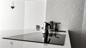 A modern kitchen with a white countertop, a stainless steel coffee maker, and a black kettle. - Discover our unique design loft in downtown Mons (Mons)