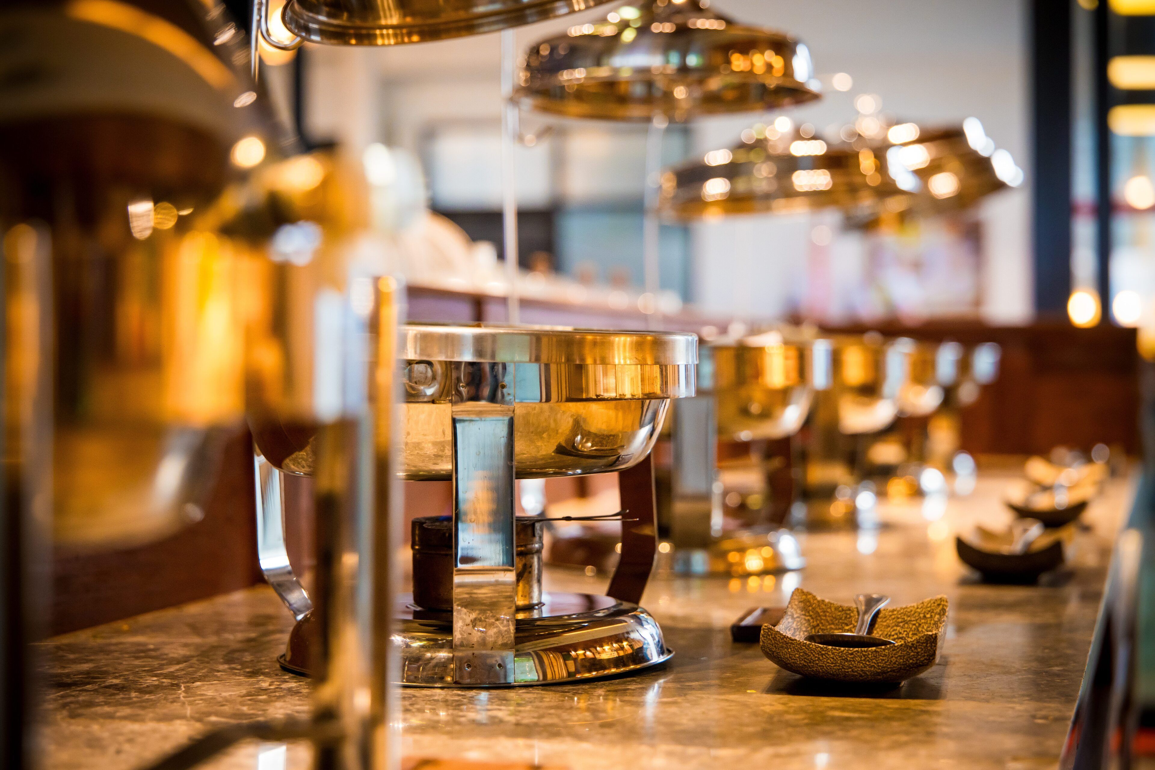 Una zona de bar con varias máquinas de café brillantes y metálicas y pequeños cuencos en la encimera.