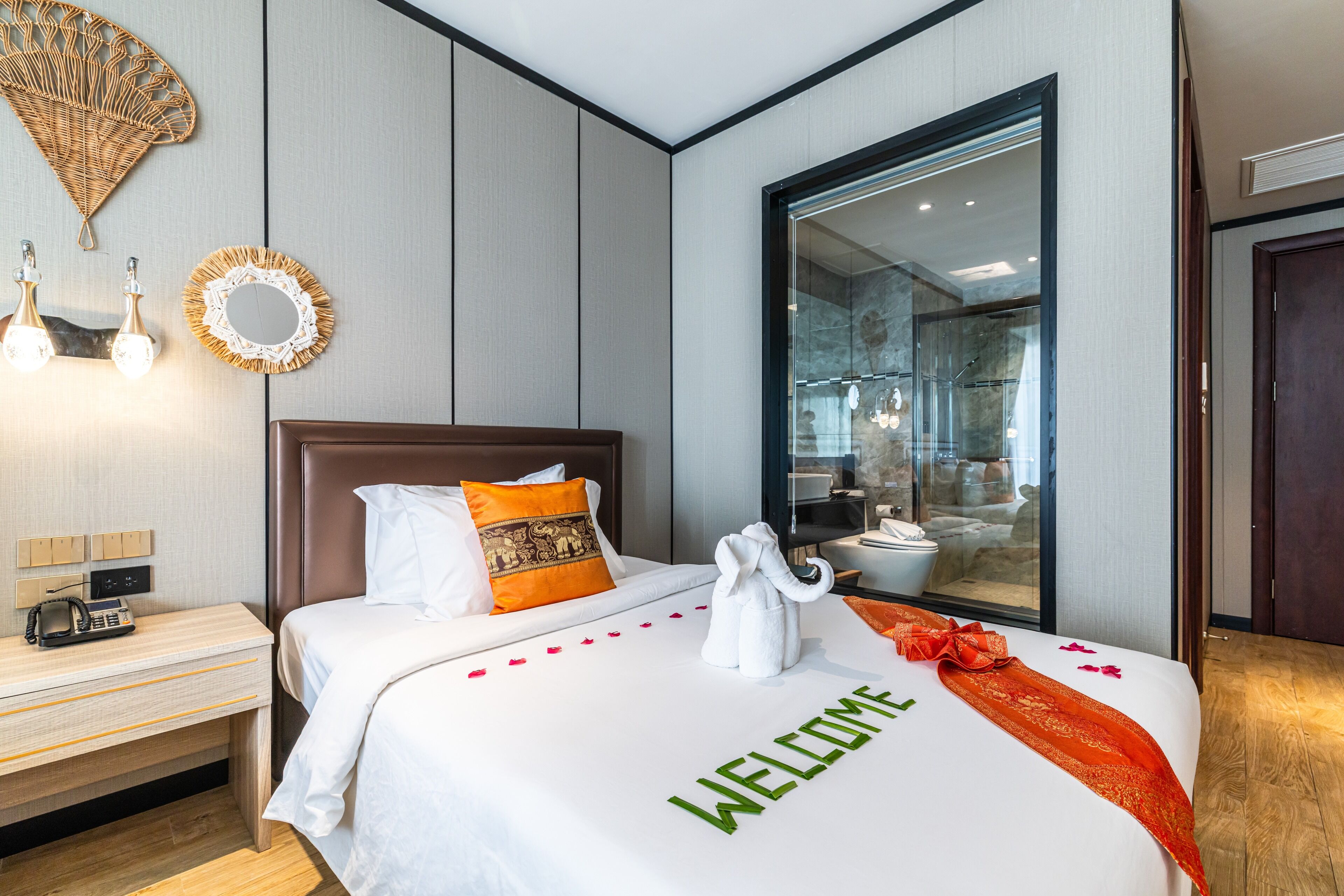 A hotel room with a large bed, a nightstand, a mirror, and a view of a bathroom through a glass door.