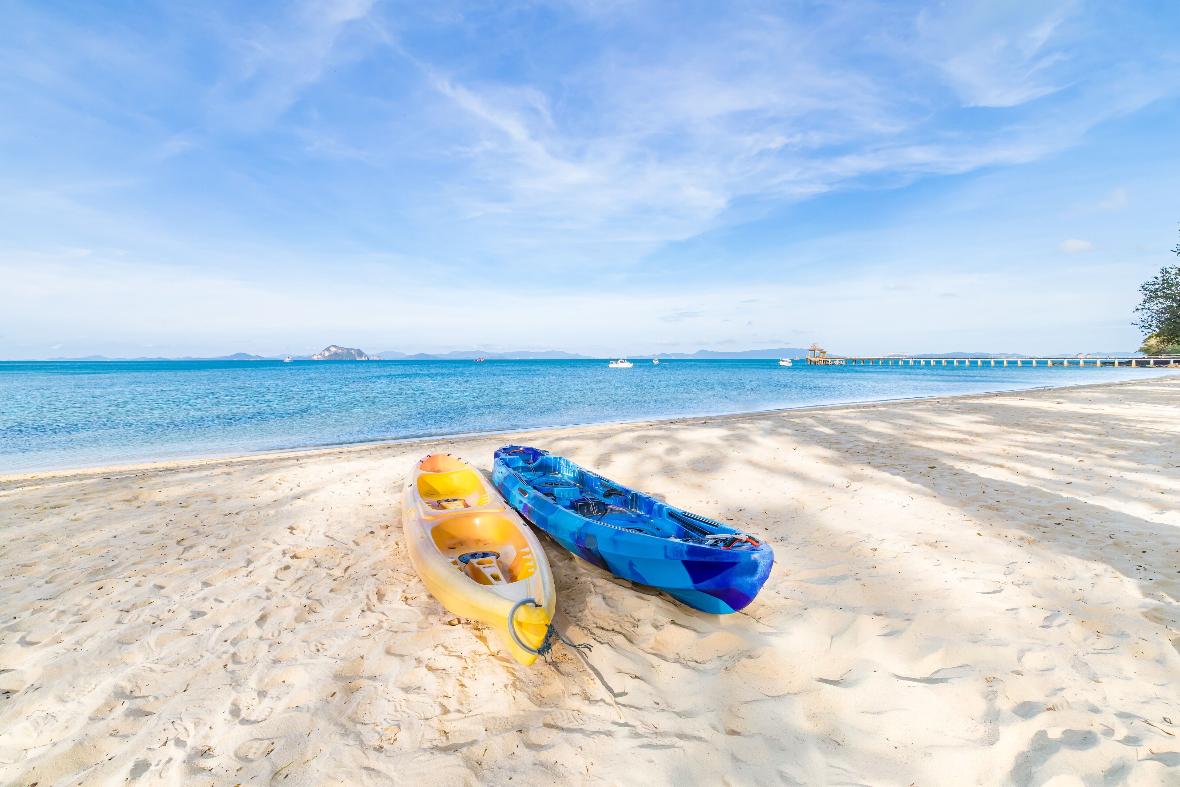 Two kayaks on a sandy beach with a clear blue sky and calm sea in the background.