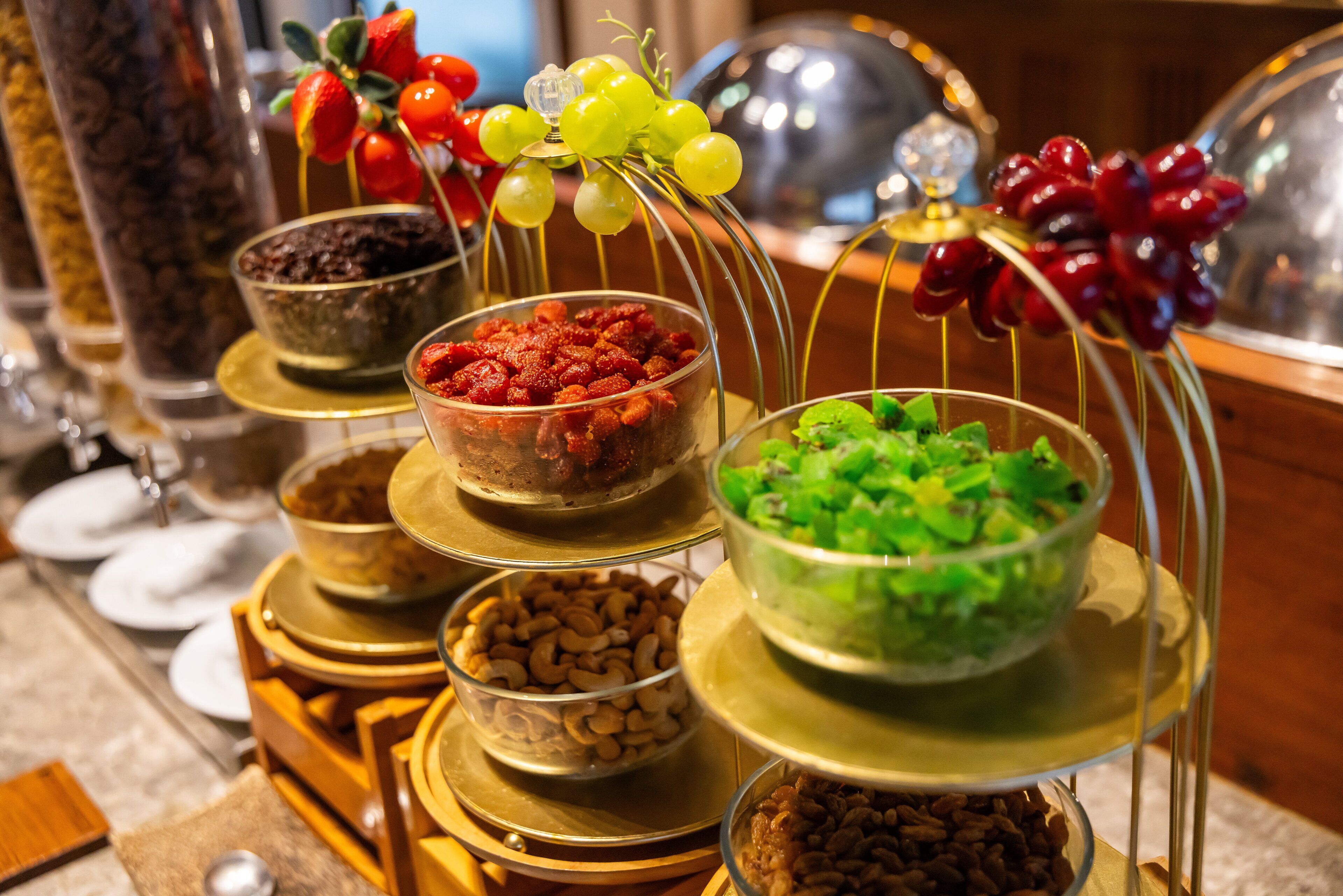 A buffet with various food items displayed on tiered stands, including nuts, dried fruits, and vegetables.