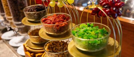 A buffet with various food items displayed on tiered stands, including nuts, dried fruits, and vegetables.