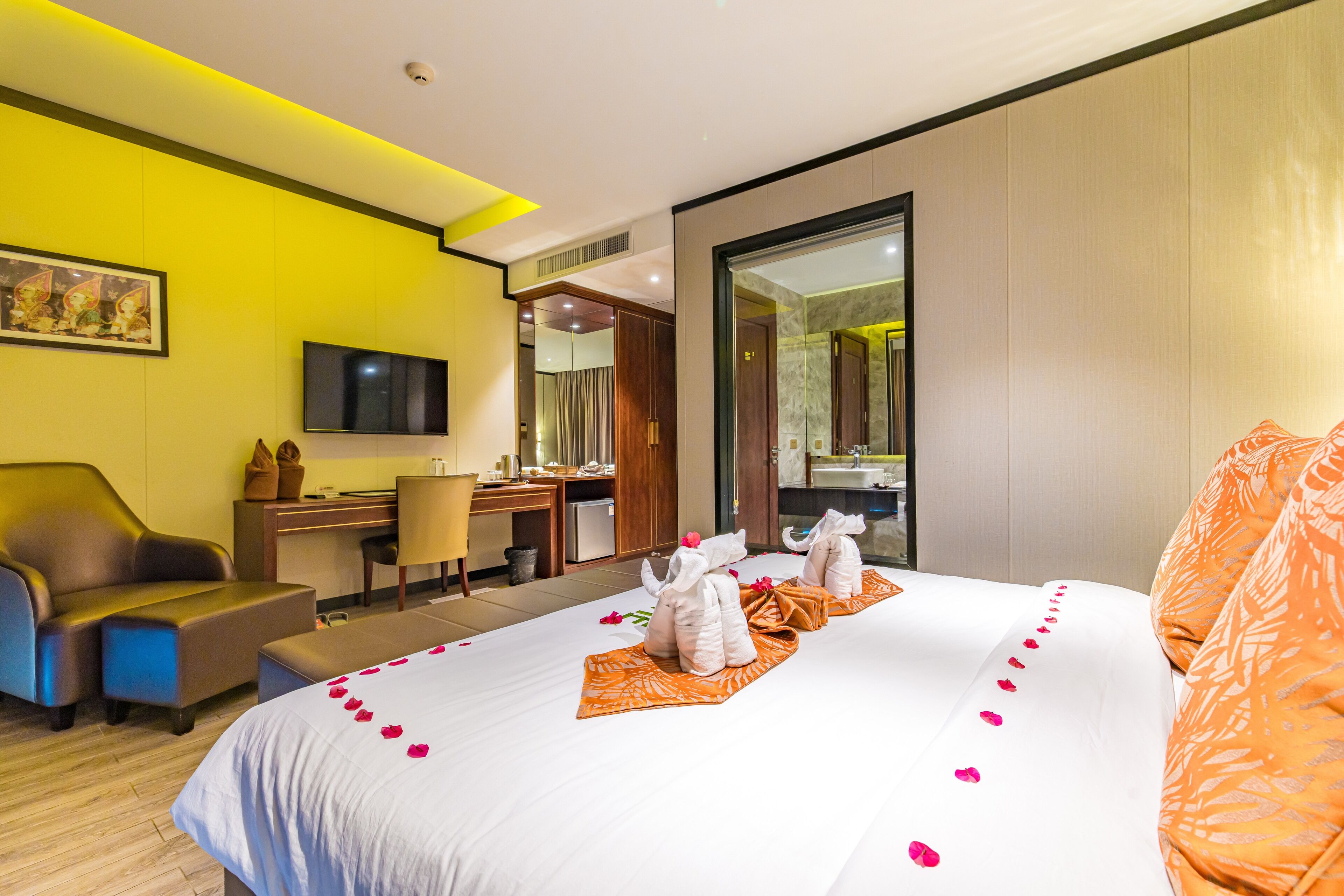 Ein Hotelzimmer mit Bett, Schreibtisch, Stuhl, Fernseher und Spiegel.