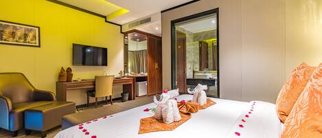A hotel room with a bed, a desk, a chair, a TV, and a mirror.
