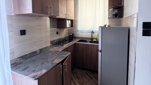 Una cocina con armarios de madera, encimera de granito, pileta de acero inoxidable y refrigerador.