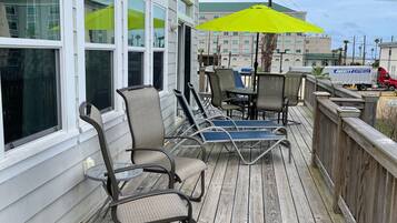 A wooden deck with outdoor furniture, including chairs and a table, and a bright yellow umbrella.