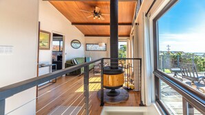 Un interior moderno con techo de madera, una chimenea central y vistas al exterior a través de amplios ventanales.