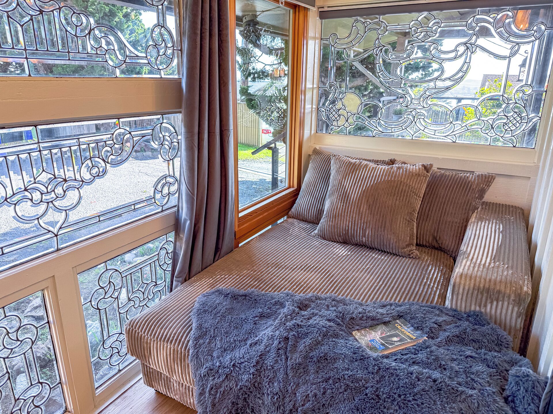 A cozy room with a cushioned bench, a fluffy throw blanket, and a book on the bench.