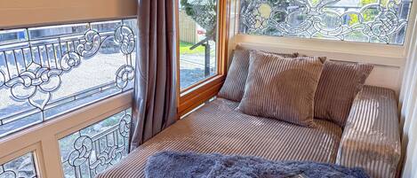 A cozy room with a cushioned bench, a fluffy throw blanket, and a book on the bench.