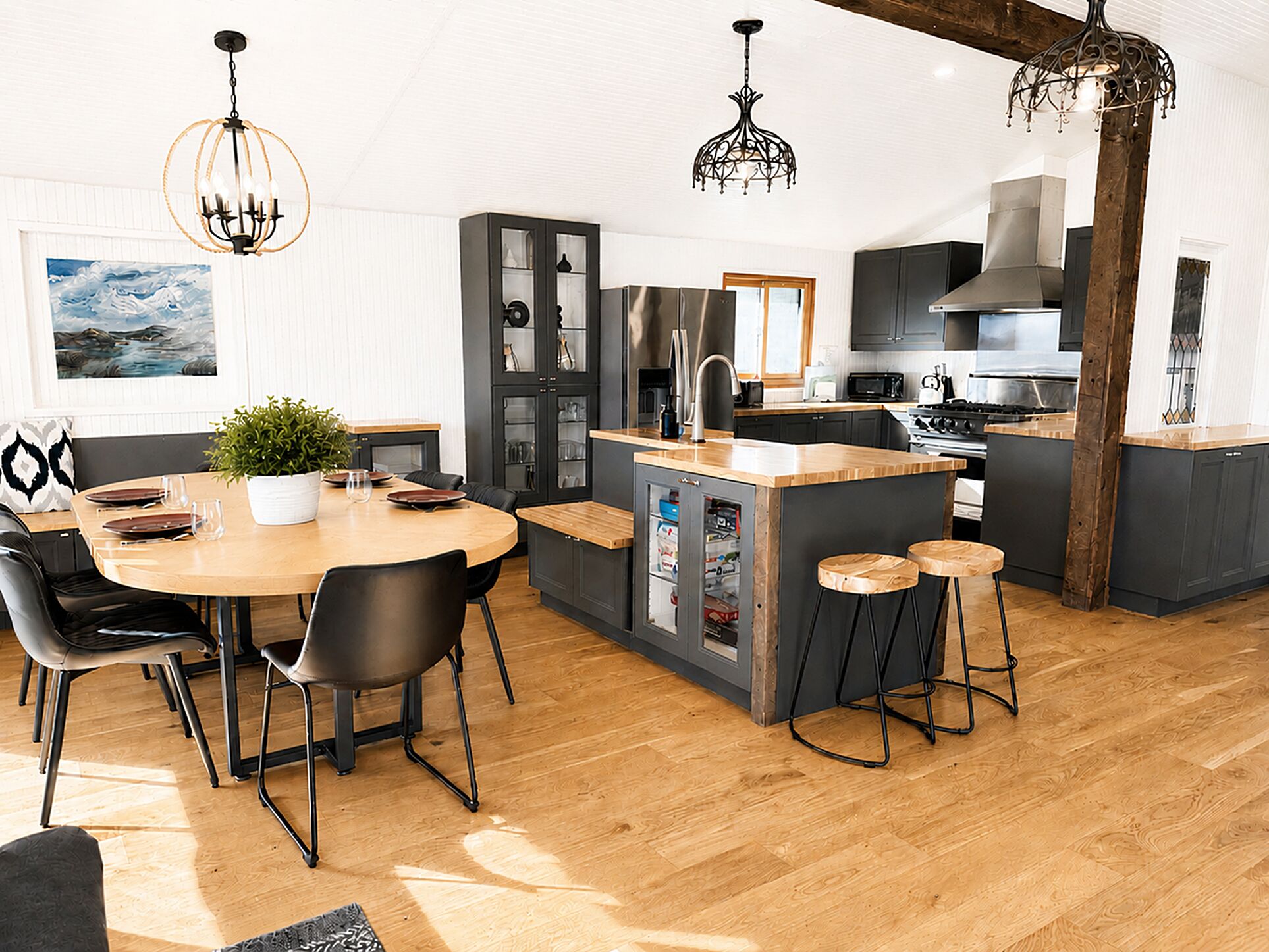 Una cocina moderna con una isla central, taburetes de bar y un comedor con sillas.