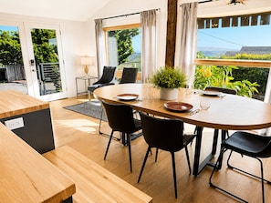 A modern dining area with a round table, black chairs, and a potted plant.