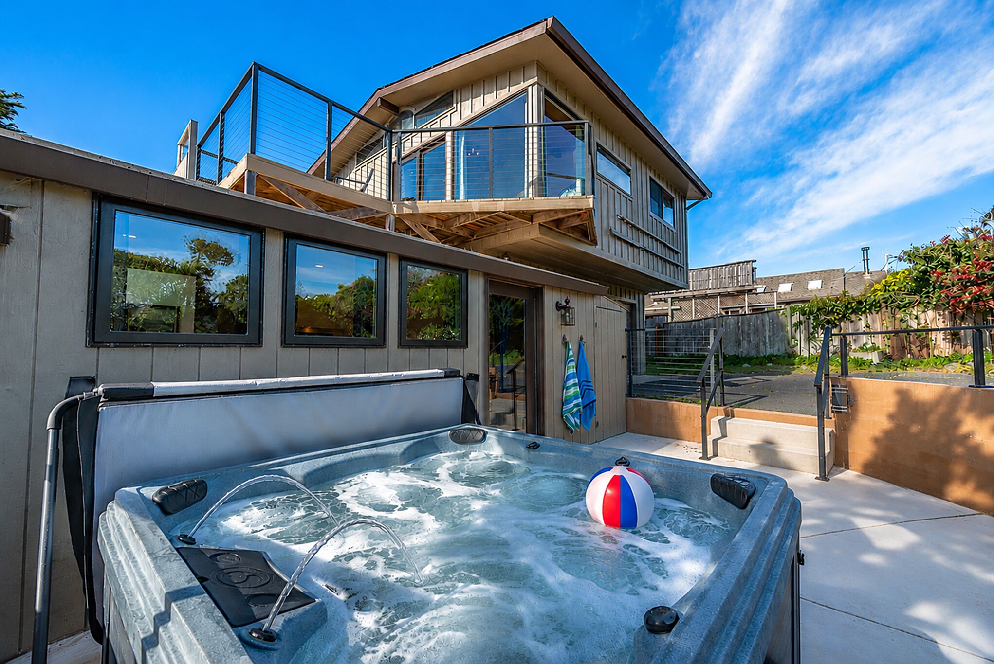 A modern building with a hot tub and a beach ball, large windows, and a balcony.