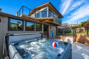 A modern building with a hot tub and a beach ball, large windows, and a balcony.