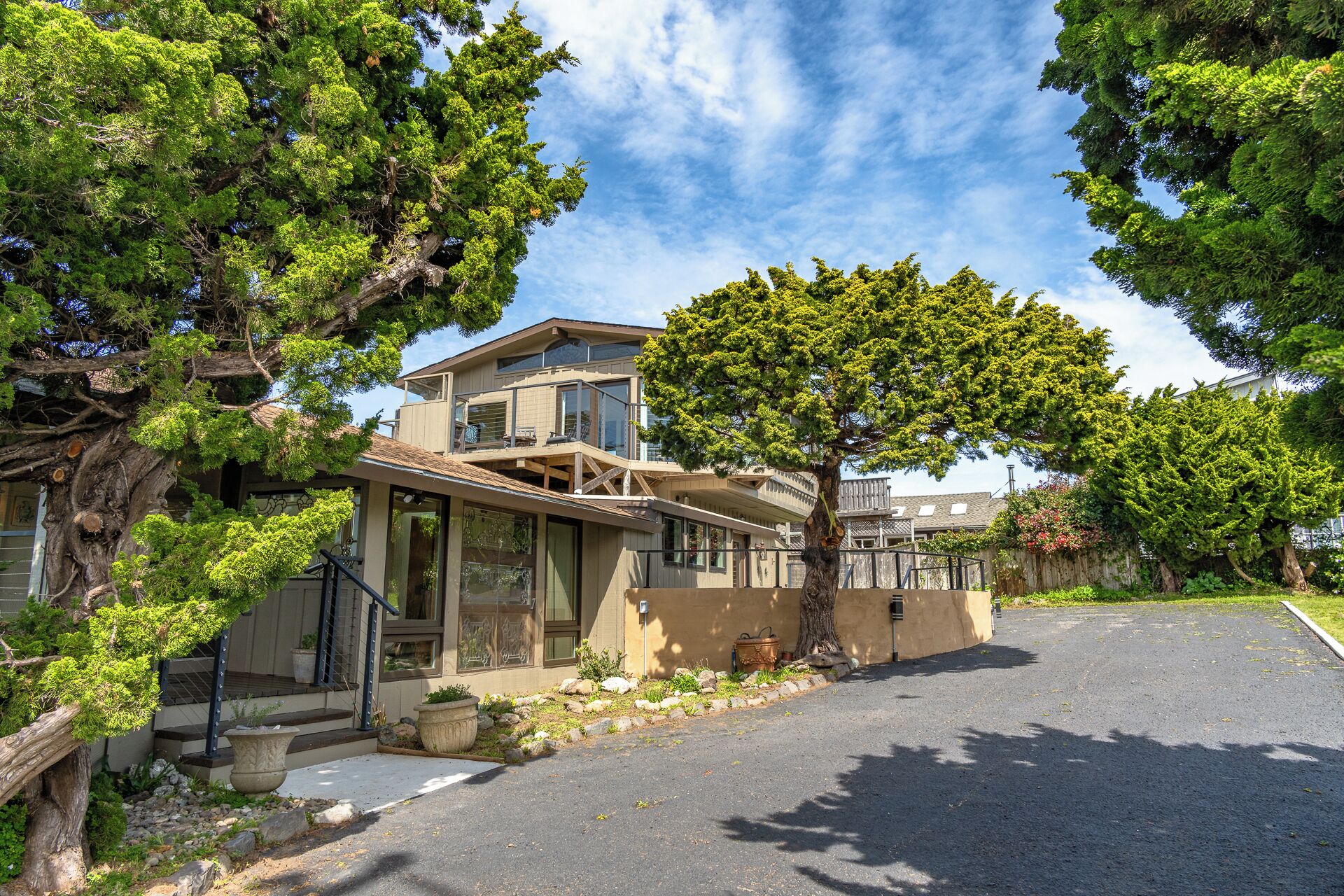 A modern two-story house with a large tree in the front yard, a covered porch, and a driveway.