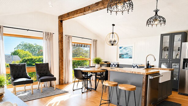 Una cocina moderna con una isla de madera, taburetes de bar y un comedor con sillas.
