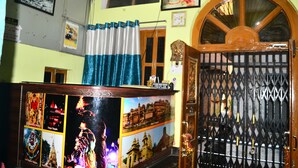A room with a wooden door, a curtain, and a wall with framed pictures. - H R Paying Guest House (Varanasi)