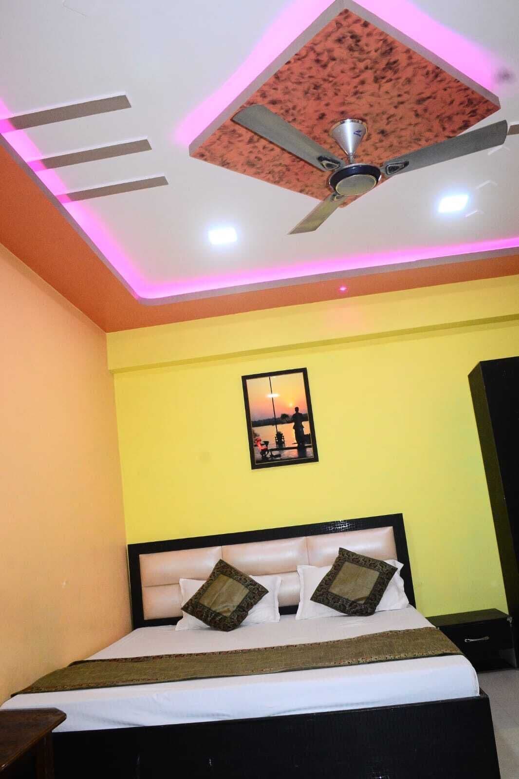 A bedroom with a bed, a ceiling fan, and a wall-mounted picture.