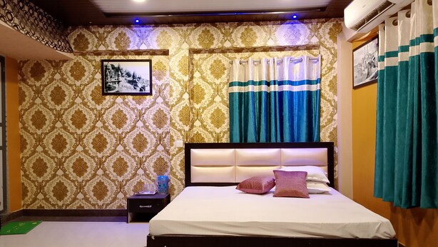A bedroom with patterned wallpaper, a bed with pillows, a nightstand, and curtains. - H R Paying Guest House (Varanasi)