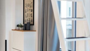 A modern interior with a white cabinet, a framed picture, a grey curtain, and a white ladder. - Cozy apartment with loft bed in Dresden Neustadt - your temporary home (Dresden)