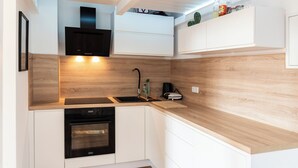 A modern kitchen with white cabinetry, a built-in oven, and a wooden countertop. - Cozy apartment with loft bed in Dresden Neustadt - your temporary home (Dresden)