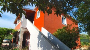 A two-story house with a red exterior, a white front porch, and a stone entrance.
