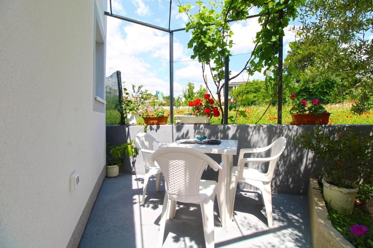 An outdoor patio with a table and chairs, surrounded by potted plants and flowers.