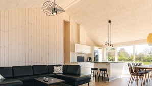 Ein modernes Wohnzimmer mit einer Eckcouch, einem Couchtisch und einem Essbereich mit Holzkohle und einem Tisch.
