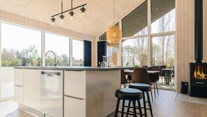 Eine moderne Küche mit einer großen Kochinsel, Barhocker, einem Essbereich und einem Kamin.