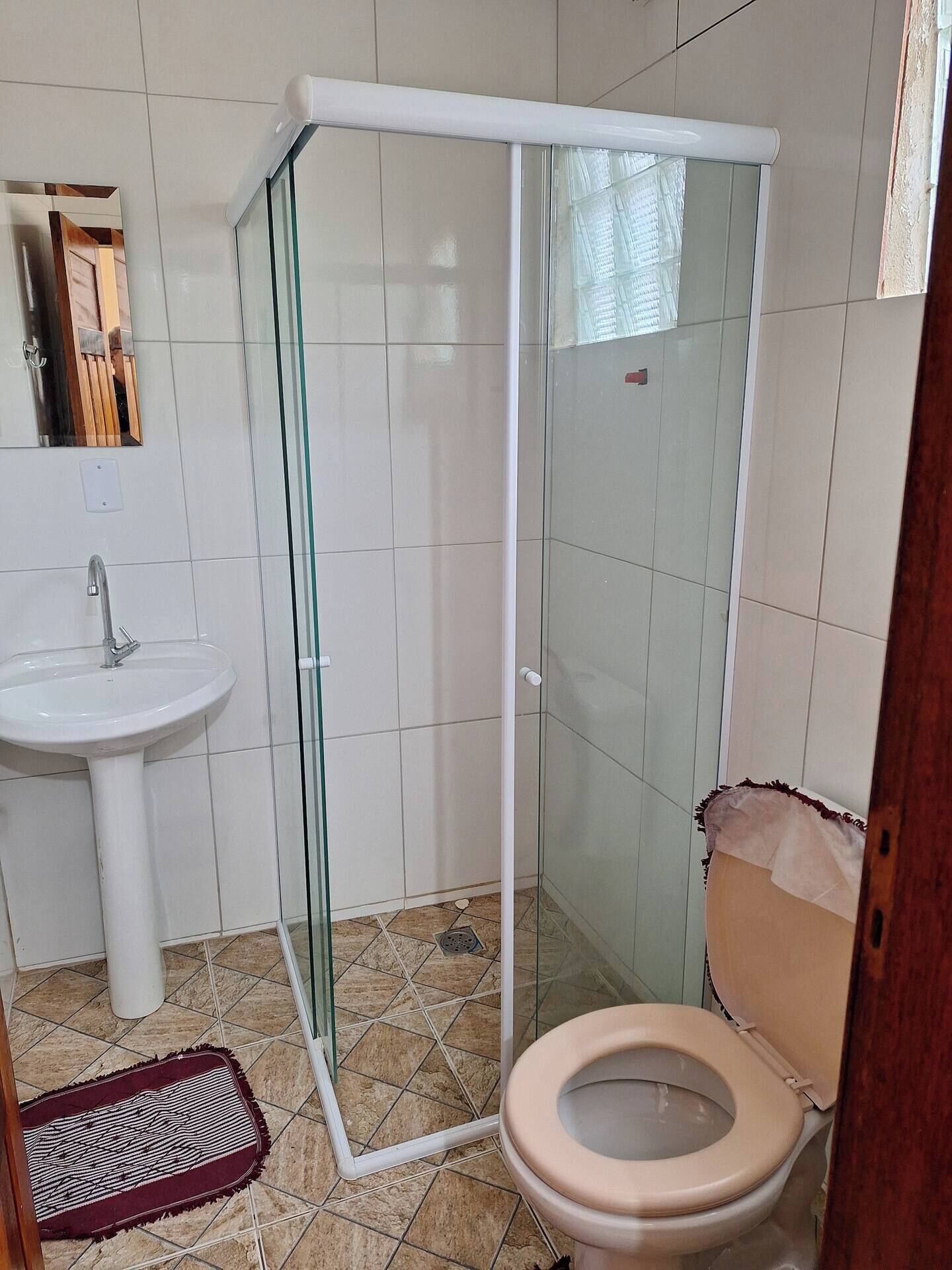 A bathroom with a glass-enclosed shower, a sink, and a toilet.