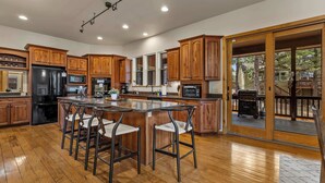 Una cocina amplia con armarios de madera, una isla central con taburetes y vistas al exterior.