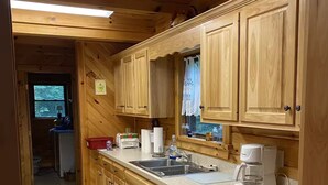 Eine Holzhütte mit einer Küche, ausgestattet mit Geschirrspüler, Spüle und einer Kaffeemaschine.