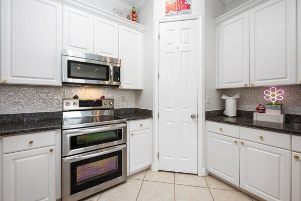 A kitchen with white cabinets, stainless steel appliances, and a granite countertop.