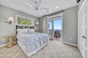 A bedroom with a bed, a ceiling fan, a window with curtains, and a view of the outdoors. - Lakefront 5BR retreat with hot tub, beach access, and water views (Miami Park area) (South Haven)