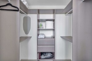 A walk-in closet with open shelving, a hanging garment, and a folded item.