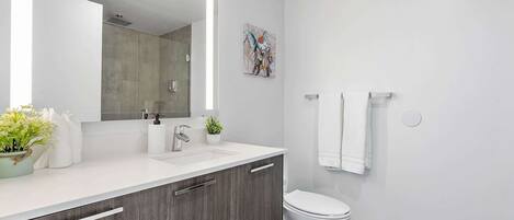 A modern bathroom with a large mirror, a toilet, and a sink.