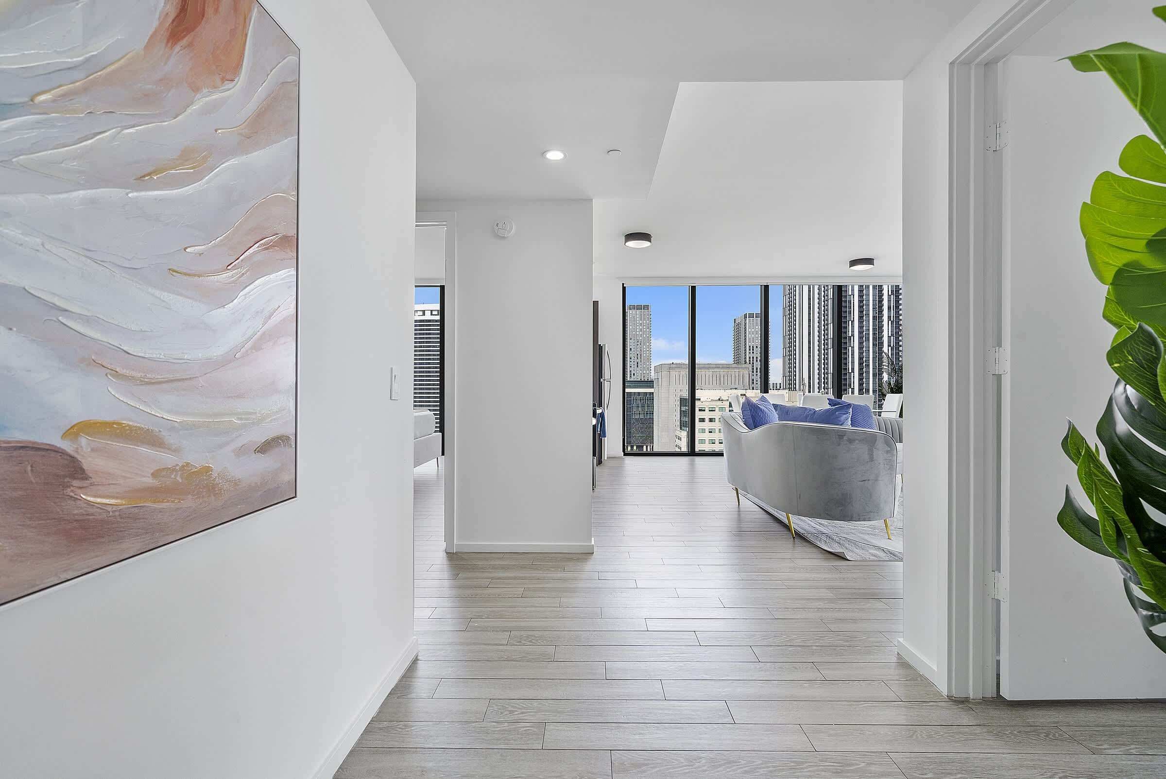 A modern interior with a hallway leading to a living area with a city view.