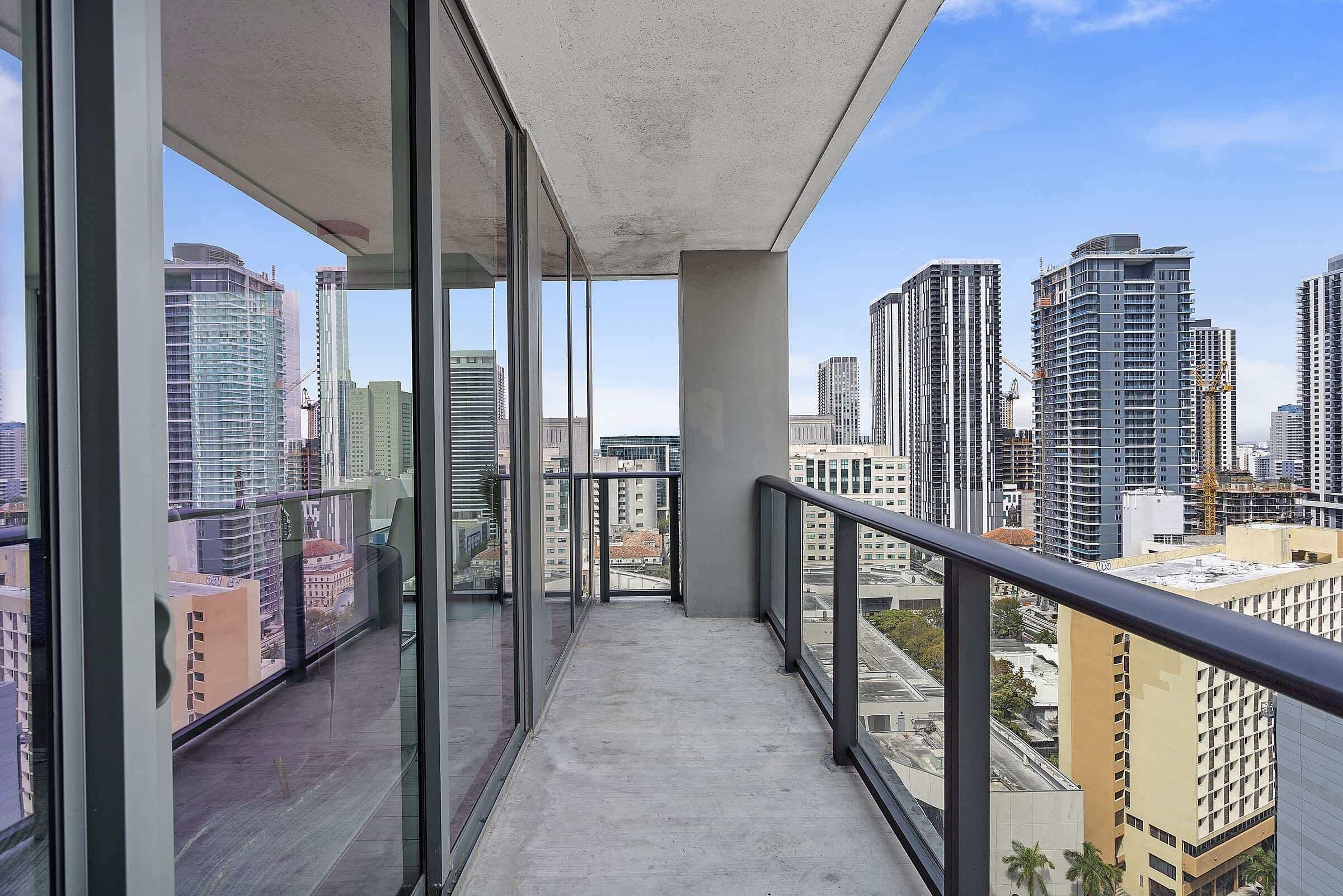 Ein Balkon mit Blick auf die Stadt, große Fenster und ein Betonboden.