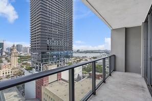 A high-rise building with a modern design, featuring a balcony with a metal railing.