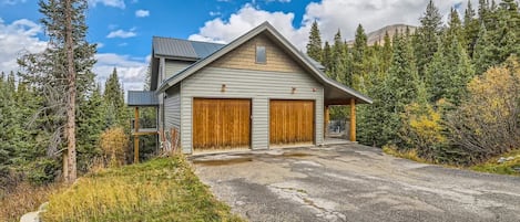 Ein zweistöckiges Haus mit Garage, umgeben von dichtem Wald.
