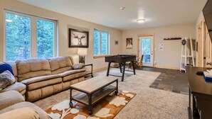 A spacious living room with a sofa, coffee table, and a pool table.