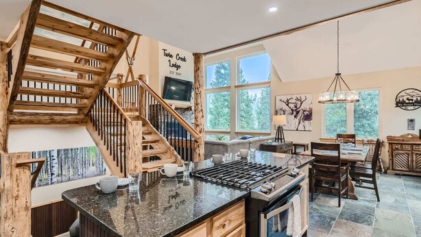 Una cocina amplia con una escalera de madera, ventanas grandes y un comedor.