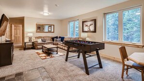 Una sala de estar acogedora con un sofá modular, una mesa de fútbol de mesa y un comedor con mesa y silla de madera.