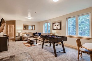 A cozy living room with a sectional sofa, a foosball table, and a dining area with a wooden table and chair. - Twin Creek Lodge (Breckenridge)