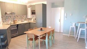 Eine moderne Küche mit Essbereich, hellem Holzboden und einer hellblauen Wand.