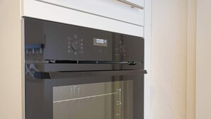 A modern black oven with a digital display and control knobs. - book2sty: Cozy Studio with kitchenette and washing machine (Herisau)